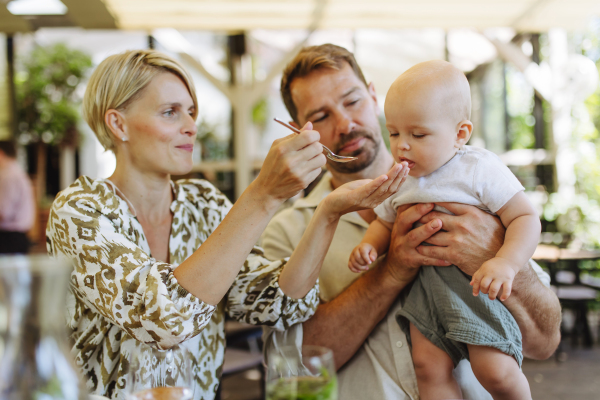 Parents in a restaurant feeding small baby. Family dinner at a restaurant.