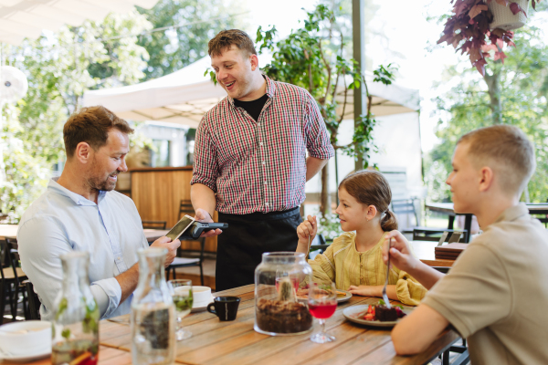 Father and children ordering food from a waiter. Single-parent family having dinner at a restaurant. Concept of Father's Day.