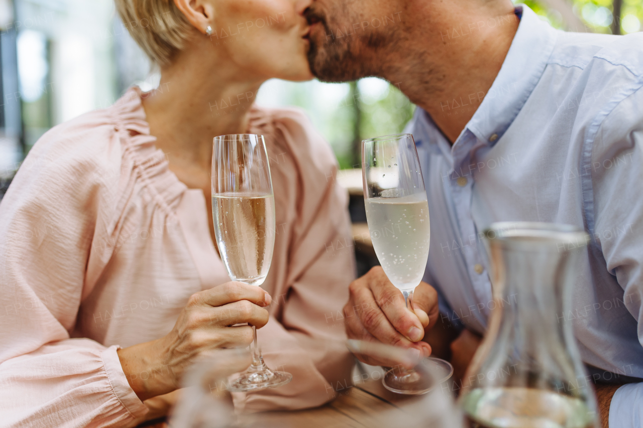 Close up of beautiful couple in a restaurant, on a romantic date. Wife and husband kissing, having a romantic moment at restaurant patio.