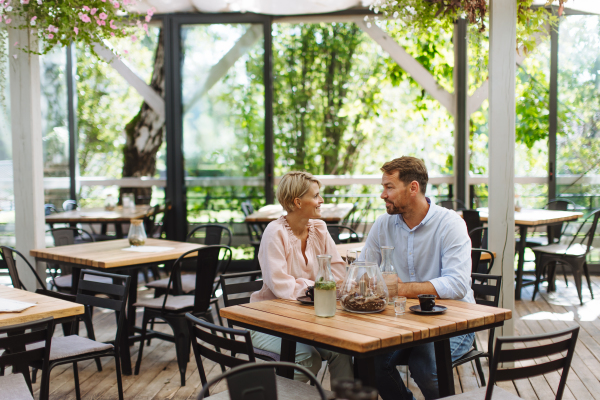 Beautiful couple in a restaurant, on a romantic date. Wife and husband kissing, having a romantic moment at restaurant patio.