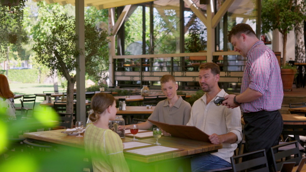 Man paying for lunch in a restaurant, paying by card. Holding card near terminal card reader.