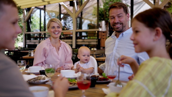 Big family with children and a small baby at family dinner in a restaurant. A small family celebration in family friendly restaurant.