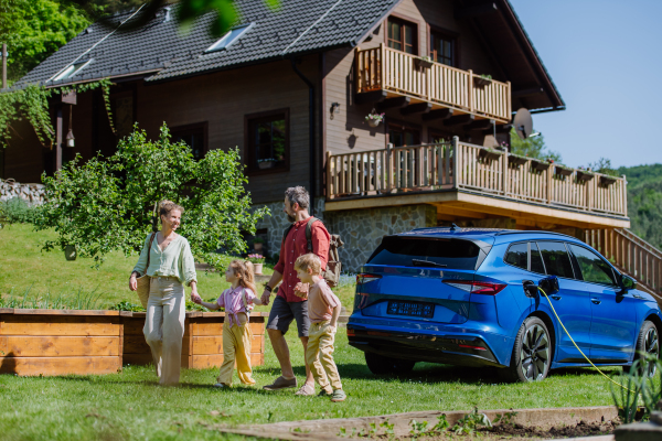 Happy family preparing for trip, charging their electric car.