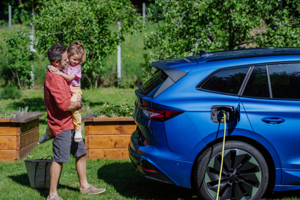 Father and his little daughter charging their electric car.