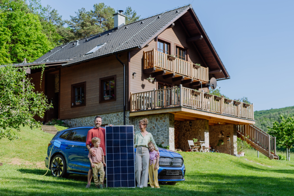 Happy family posing with a photovoltaics panel during their electric car charging.