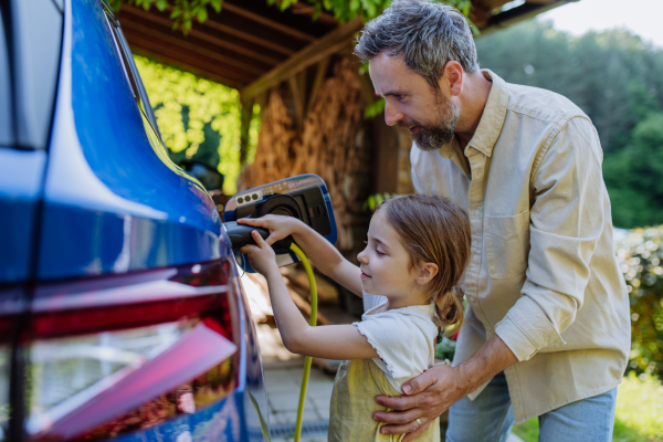 Father and his little daughter charging their electric car.