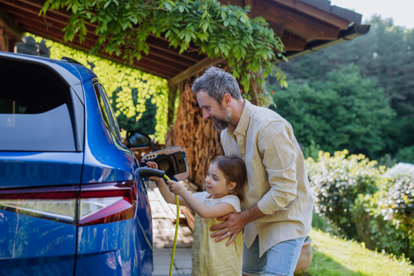 Father and his little daughter charging their electric car.