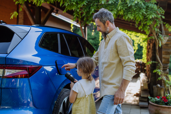 Father and his little daughter charging their electric car.