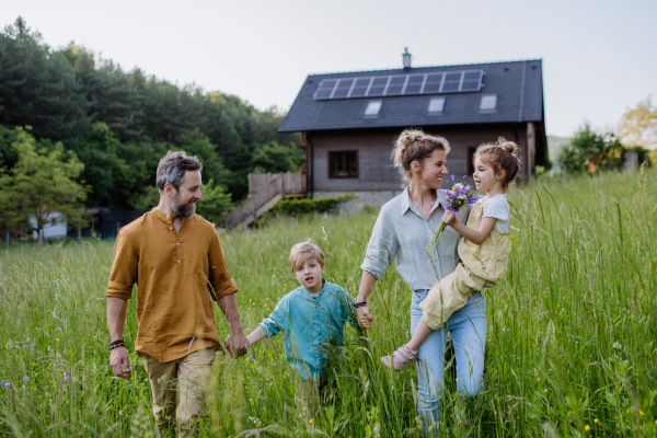 Happy family in front of their house with a solar panels on the roof.