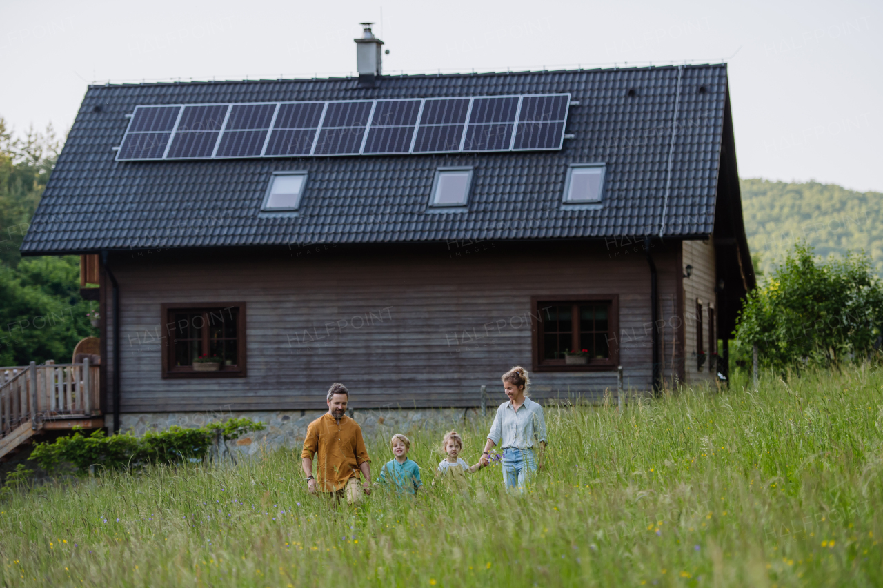 Happy family in front of their house with a solar panels on the roof.