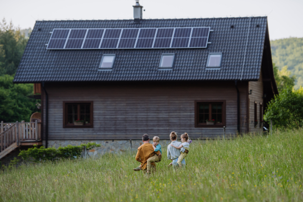 Happy family in front of their house with a solar panels on the roof.