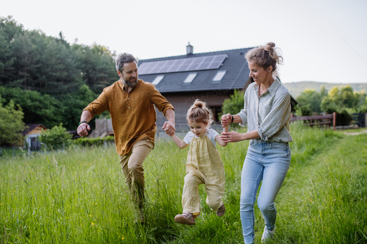 Family walking near their house with photovoltiacs panels on a roof.