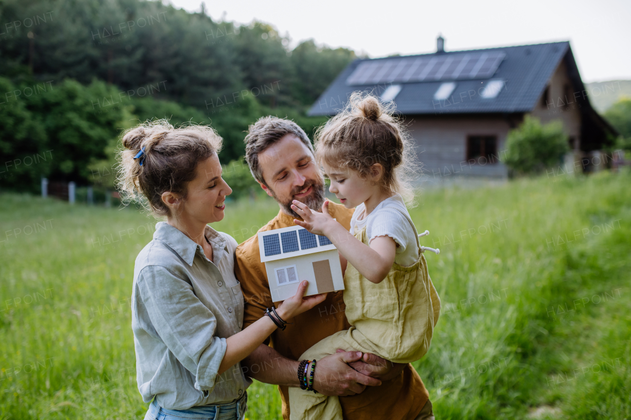 Happy family in front of their house with a solar panels on the roof.