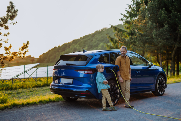 Father and his son charging teir electric car during trip.