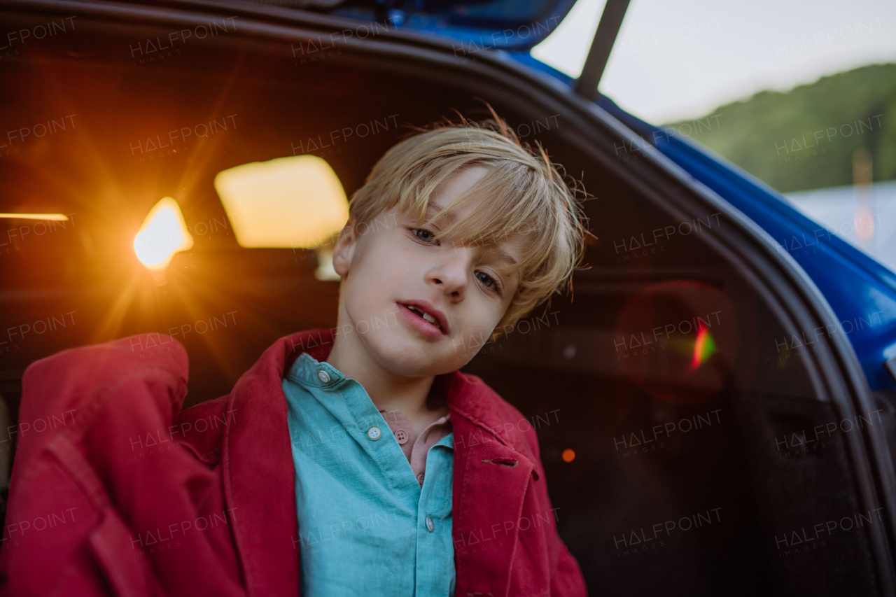 Close up of a little boy sitting in a car trunk.