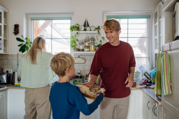 Young family preparing breakfast together in home kitchen. Healthy breakfast or snack before kindergarden, school and work.