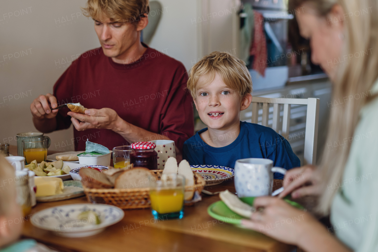 Young family eating breakfast together in home kitchen. Healty breakfast or snack before school and work.