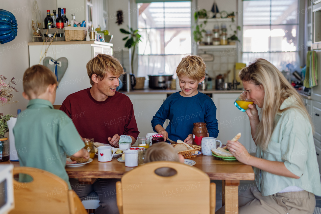 Young family eating breakfast together in home kitchen. Healthy breakfast or snack before kindergarden, school and work.