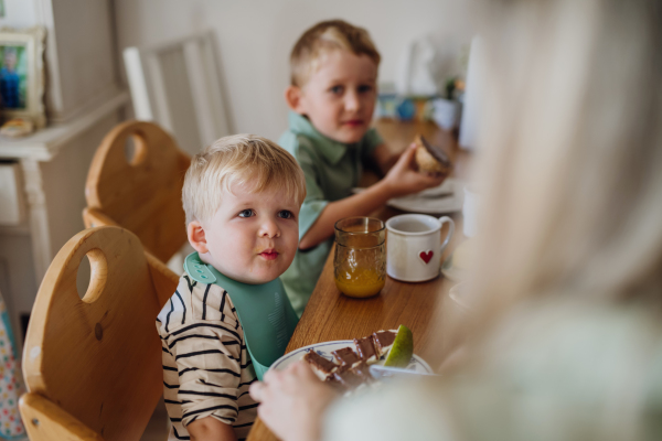 Young family eating breakfast together in home kitchen. Healthy breakfast or snack before preschool, school and work.