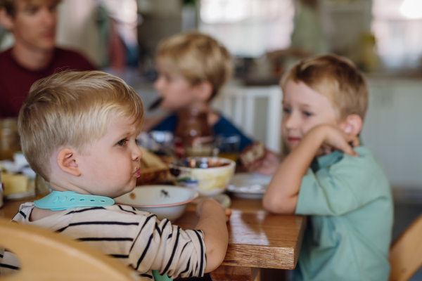 Young family eating breakfast together in home kitchen. Healty breakfast or snack before school and work.