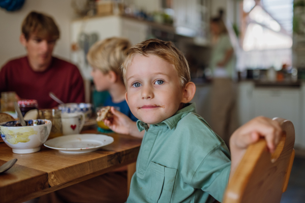 Young family eating breakfast together in home kitchen. Healty breakfast or snack before school and work.