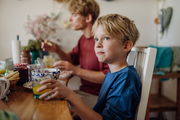 Young family eating breakfast together in home kitchen. Healty breakfast or snack before school and work.