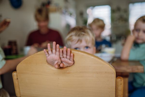 Little boy eating breakfast, hands through hole in the chair. Healthy breakfast or snack before day care.