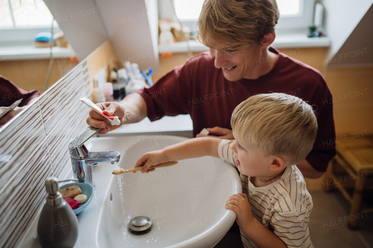 Father brushing little baby boy's teeth in the morning. Morning dental hygiene, care for toddlers.