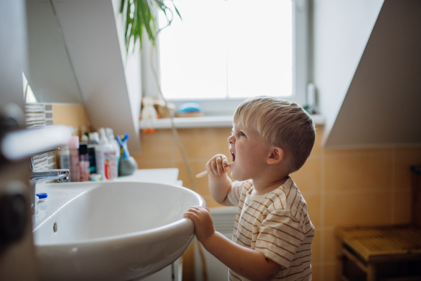 Toddler brushing teeth in the morning, without help. Morning dental hygiene for toddlers.