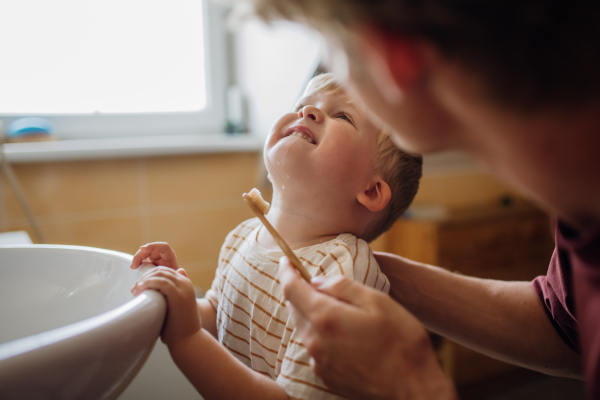 Father brushing little baby boy's teeth in the morning. Morning dental hygiene, care for toddlers.