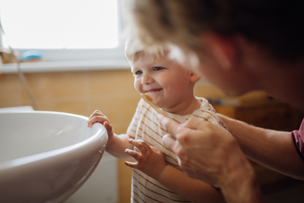 Father brushing little baby boy's teeth in the morning. Morning dental hygiene, care for toddlers.