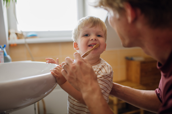 Father brushing little baby boy's teeth in the morning. Morning dental hygiene, care for toddlers.