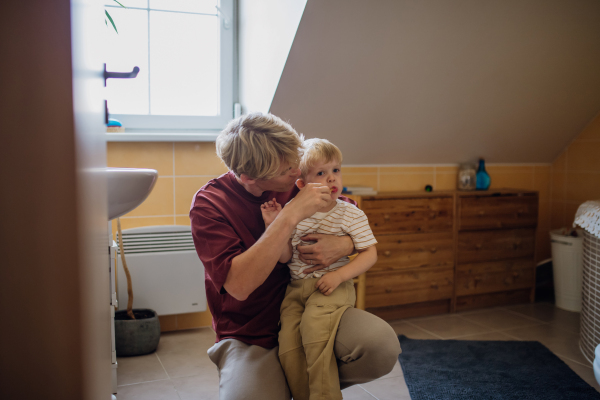 Father brushing little baby boy's teeth in the morning. Morning dental hygiene, care for toddlers.