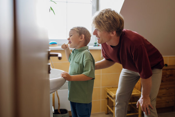 Father helping brush boy's teeth in the morning. Morning dental hygiene, care for toddlers.