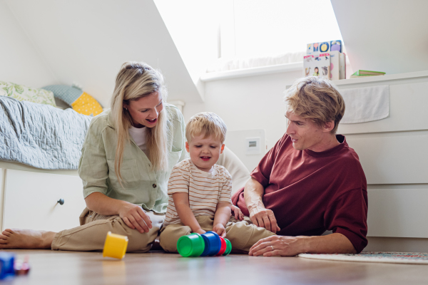 Parents looking at little boy building a tower in childrens room. Stacking blocks, building game for the preschooler.