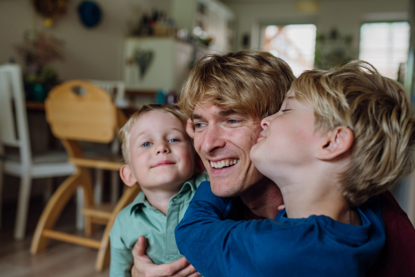 Two sons kissing father's cheeks affectionately. Concept of Father's Day, and fatherly love.