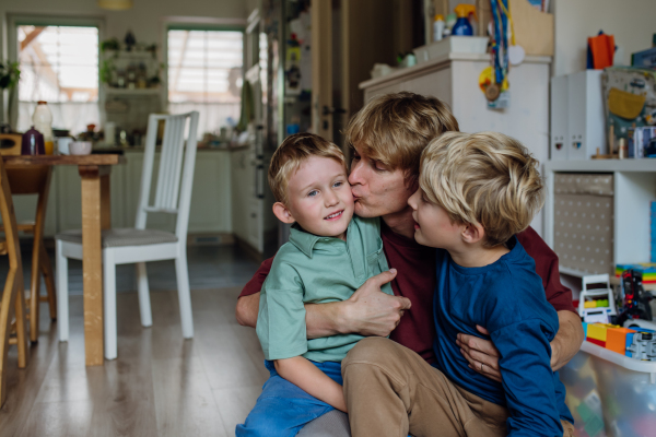 Father hugging sons and kissing one son's cheeks. Concept of Father's Day, and fatherly love.