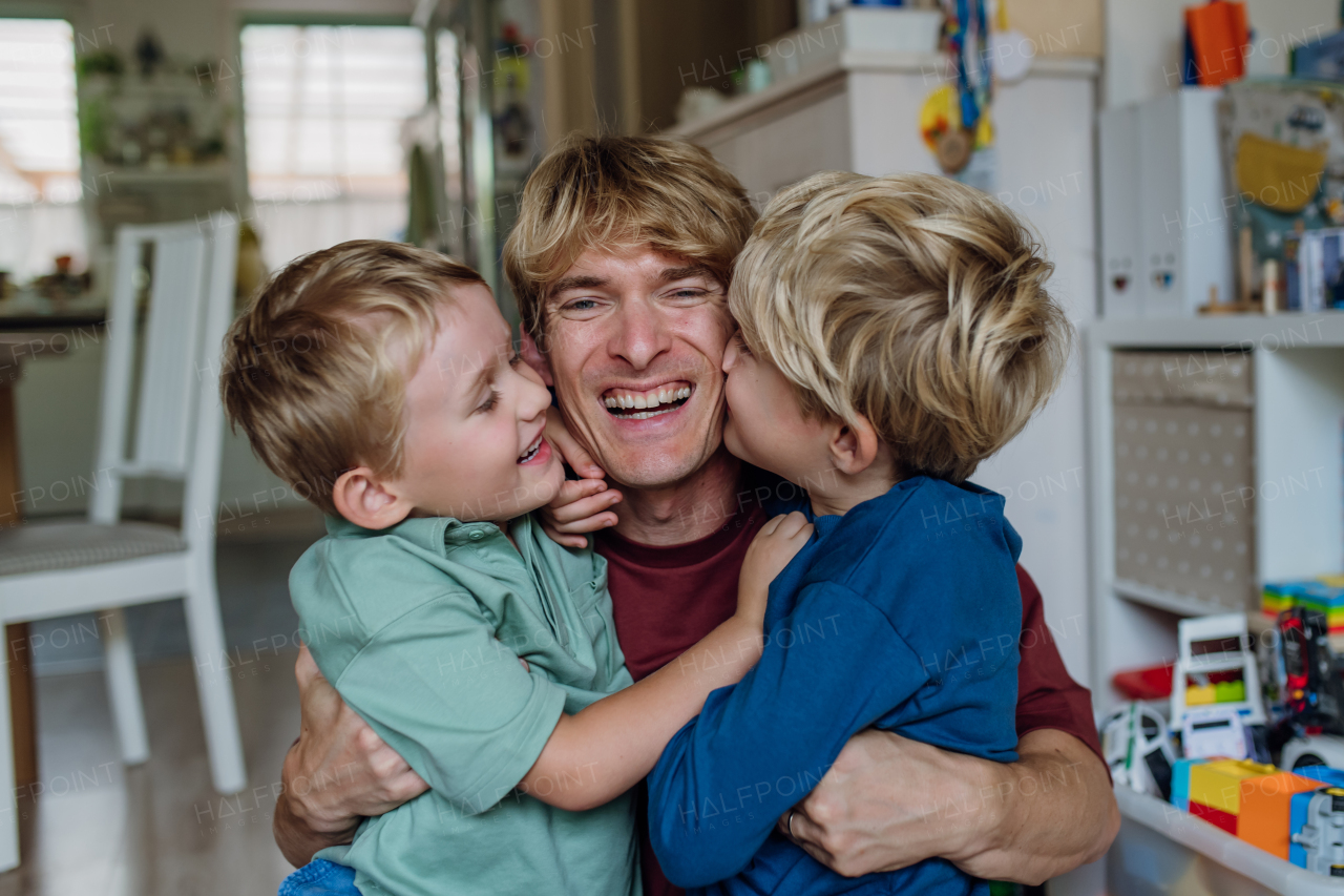 Two sons kissing father's cheeks affectionately. Concept of Father's Day, and fatherly love. Real family, real people.