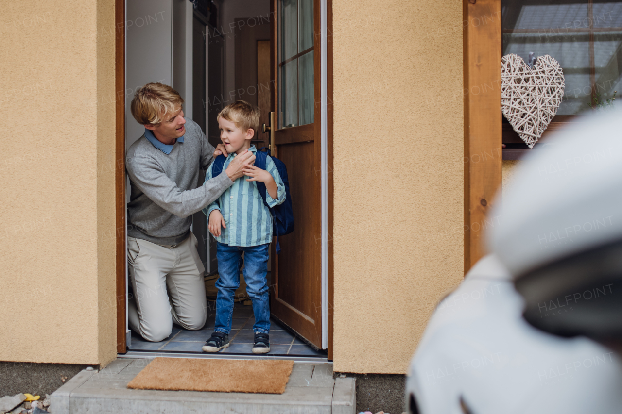 Boy getting ready for school, putting on the shoes, getting dressed. Father taking son to school before going to work.