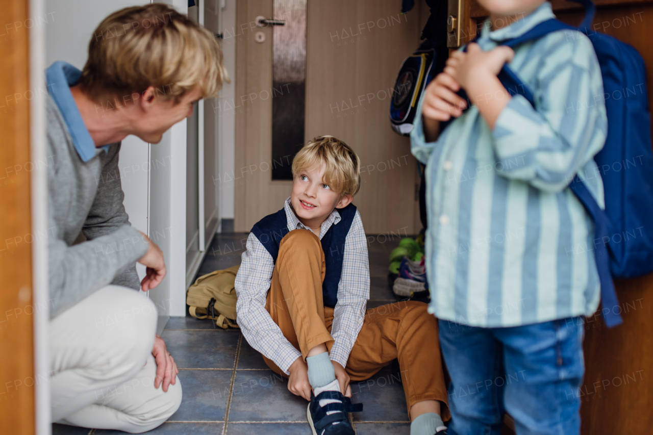 Children getting ready for school, putting on the shoes, getting dressed. Father taking them to school and kindergarten before going to work.