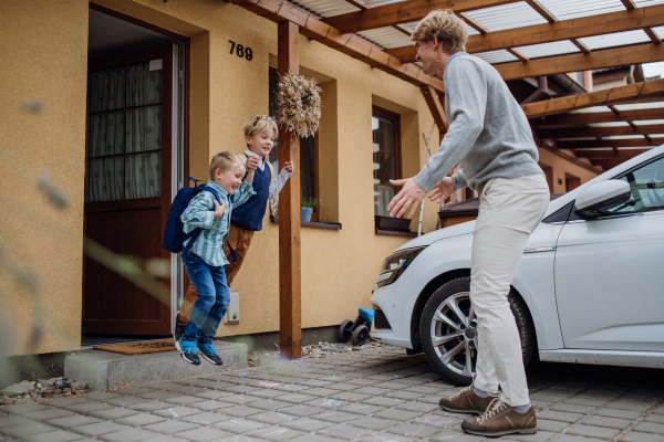 Children getting ready for school, sons jumping from stair. Father taking them to school and kindergarten before going to work.