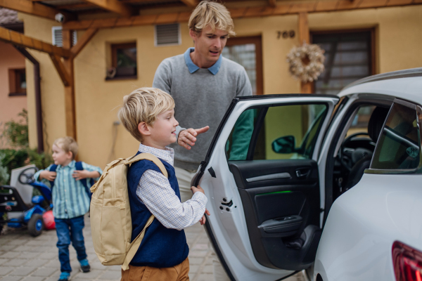 Children getting into the car, father is taking them to school and kindergarten before going to work.