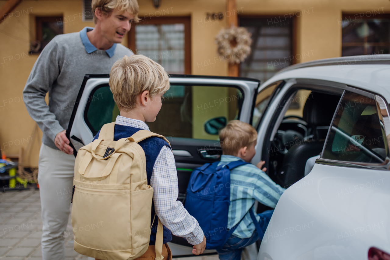 Children getting into the car, father is taking them to school and kindergarten before going to work.