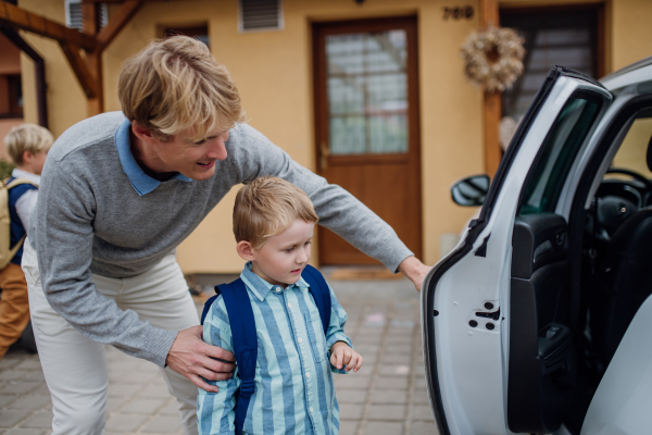 School boy getting into the car, dad helping. Father taking son to school before going to work.