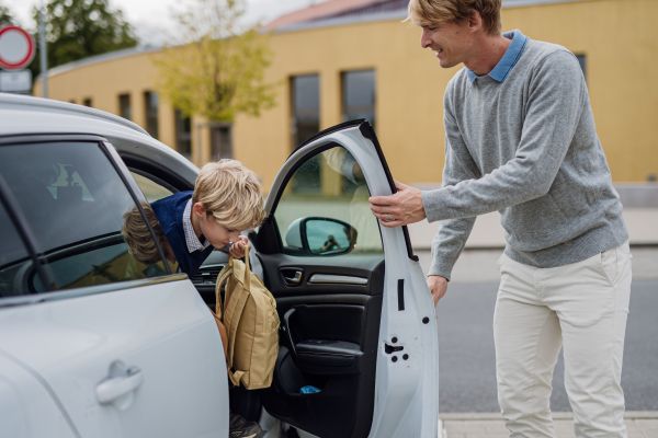 Children getting into the car, father is taking them to school and kindergarten before going to work.