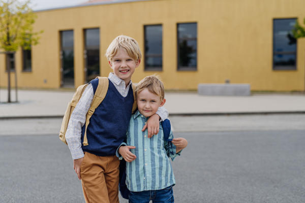 Portrait of two brothers in front of school building. Dad heading to work. Concept of work-life balance for parents.