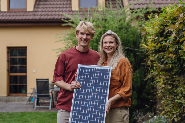 Woman and man holding solar panel in the garden, concept photovoltaics and green energy for the family.