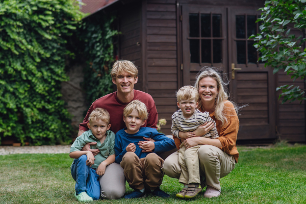 Portrait of family sitting in the garden on the grass. Beautiful mother with her three sons and husband in the living room.