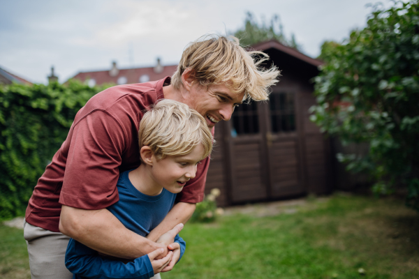 Father embracing his young son in the garden, having bonding moment. Concept of Father's Day, and fatherly love.