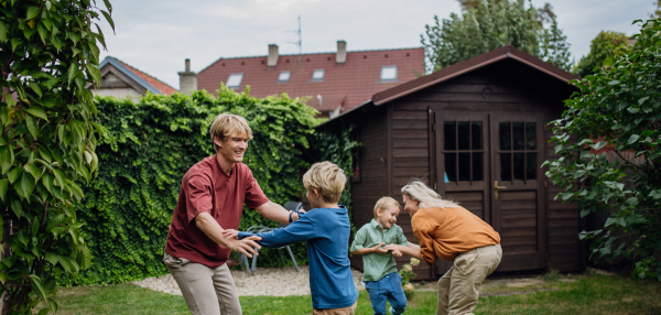 Parents having fun with sons in the garden, bonding moment. Concept of the nuclear family.